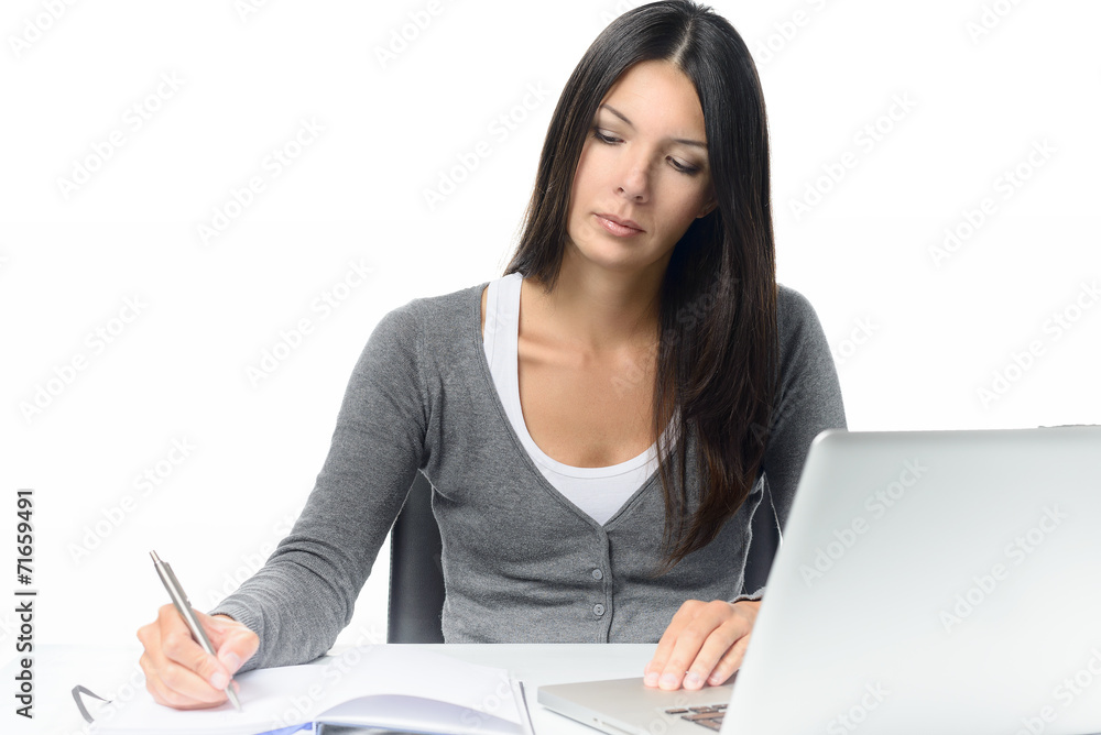 Ernste junge Frau arbeitet mit Laptop und Notizblock