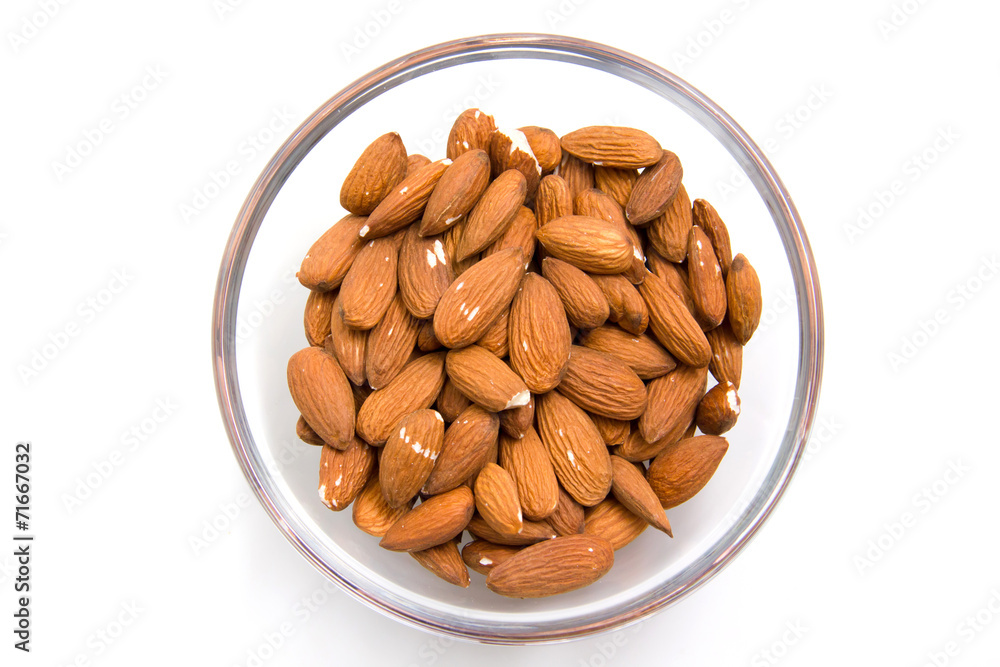 Almonds in glass bowl on white background from above Almonds in glass bowl on white background from above