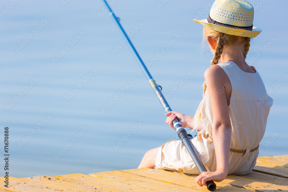 Girl in a dress and a hat with a fishing rod Girl in a dress and a hat with a fishing rod