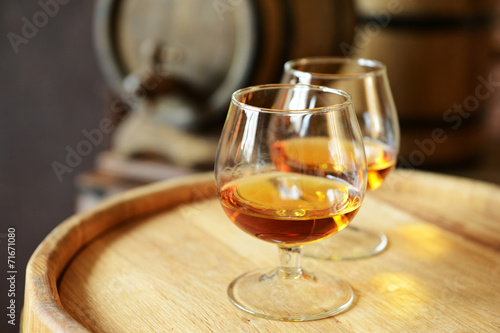 Glasses of brandy in cellar with old barrels photo