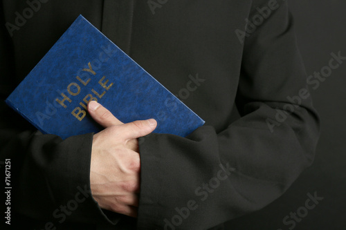 Man holding Bible on dark background