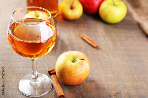 Apple cider in wine glass and bottle, with cinnamon sticks and