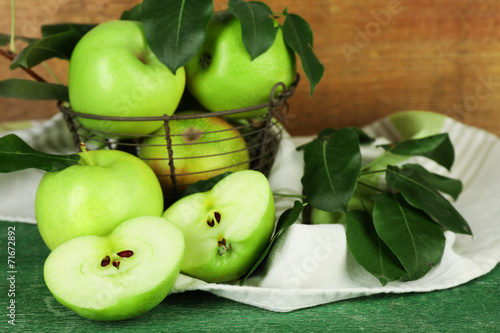 Ripe apples in metal basket with napkin on wooden background