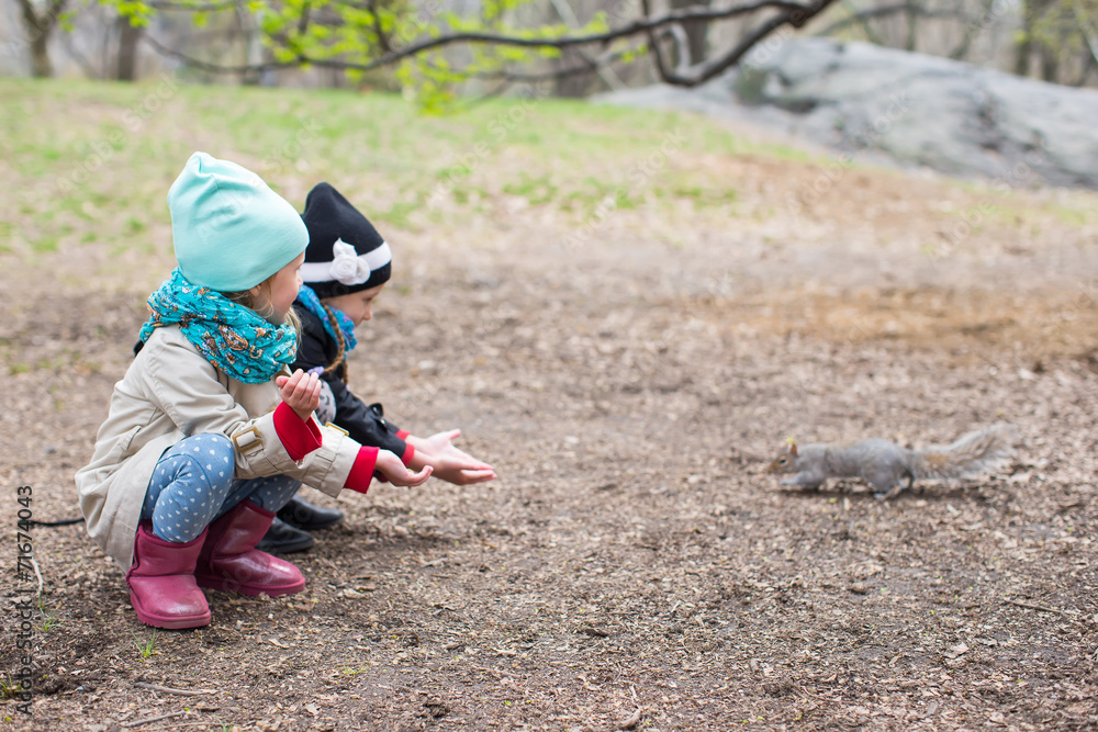 Little girls feeds a squirrel in Central park, New York, America Little girls feeds a squirrel in Central park, New York, America