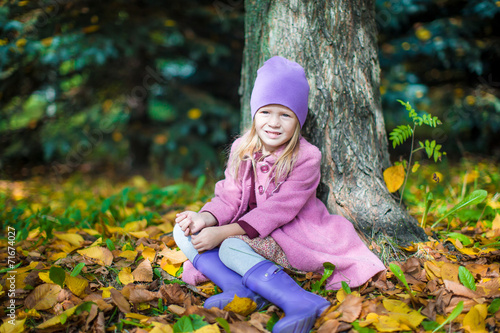 Little happy girl in autumn park on sunny fall day