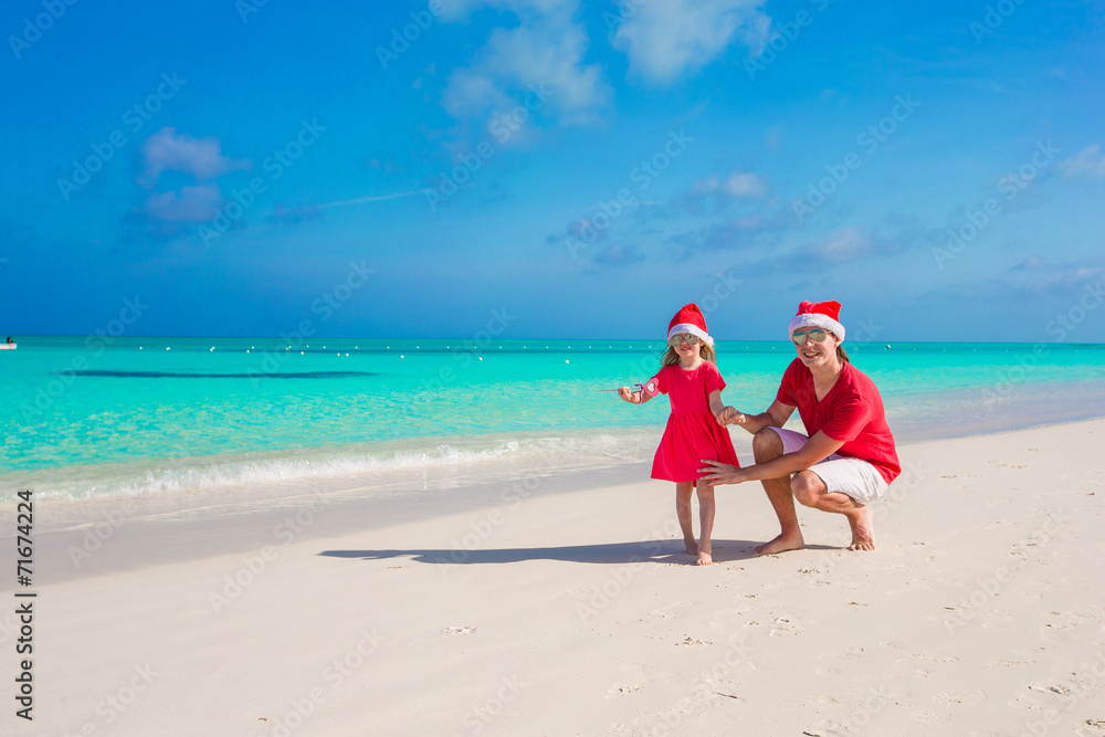 Little girl and happy dad in Santa Hat at exotic beach Little girl and happy dad in Santa Hat at exotic beach