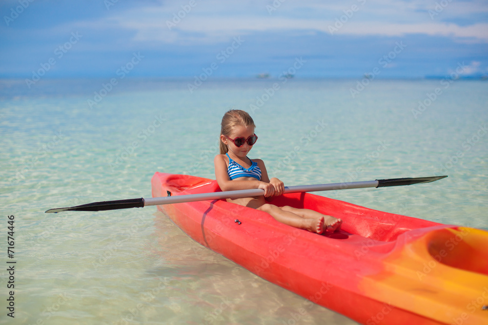 Little adorable girl kayaking in clear blue sea