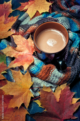 Cup of coffee set with autumn leaves and a warm scarf