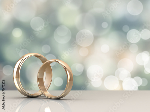 Fototapeta A pair of gold wedding rings with bokeh background