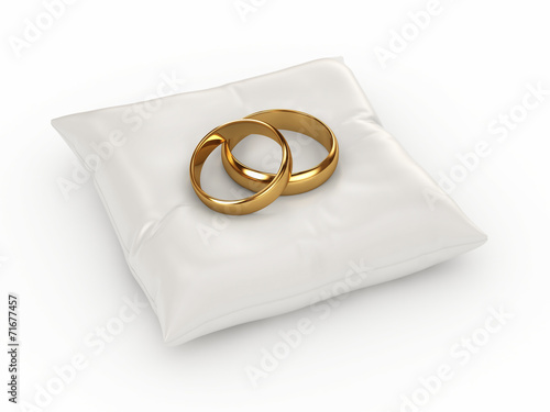 A pair of gold wedding rings on top of a pillow