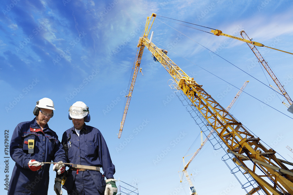 construction workers and giant mobile cranes construction workers and giant mobile cranes