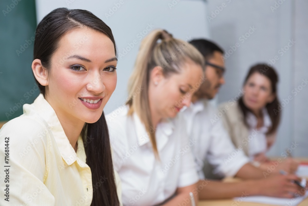 Businesswoman smiling at camera with team behind her Businesswoman smiling at camera with team behind her