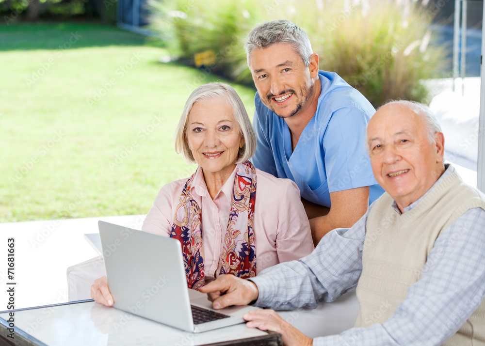 Caretaker And Senior Couple With Laptop At Nursing Home Caretaker And Senior Couple With Laptop At Nursing Home