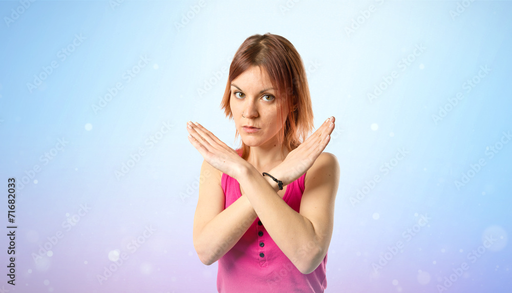 Redhead girl doing NO gesture over blue background