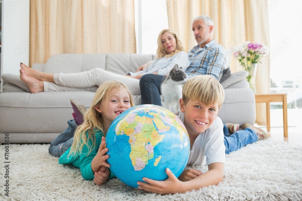 Fototapeta premium Siblings looking at globe on the floor