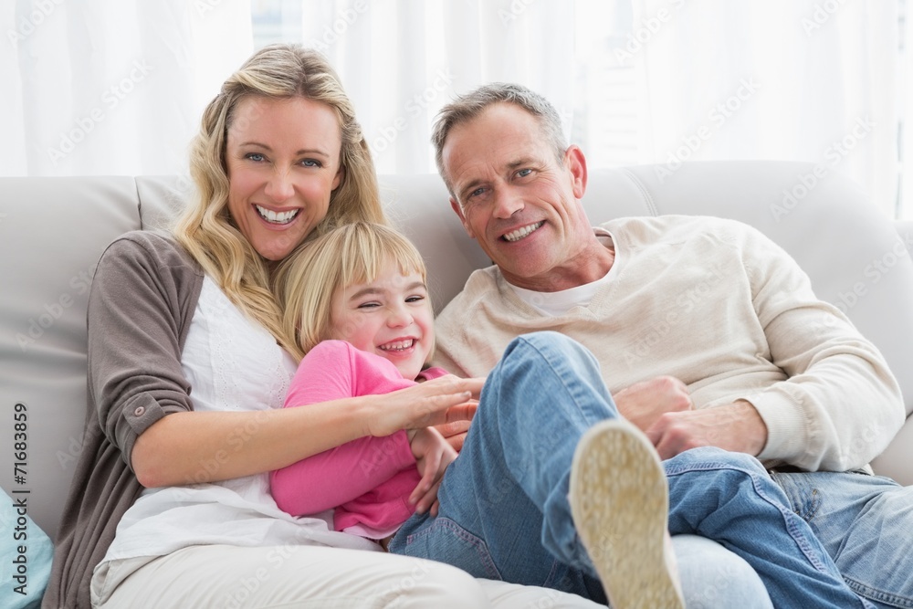 Happy parent tickling their cute daughter on the couch Happy parent tickling their cute daughter on the couch