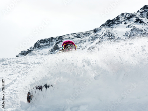 Woman snowboarder in motion in mountains photo
