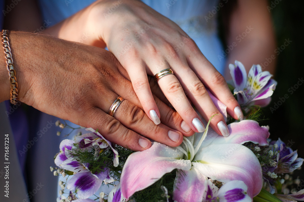 Fototapeta premium two hands with wedding rings and flowers