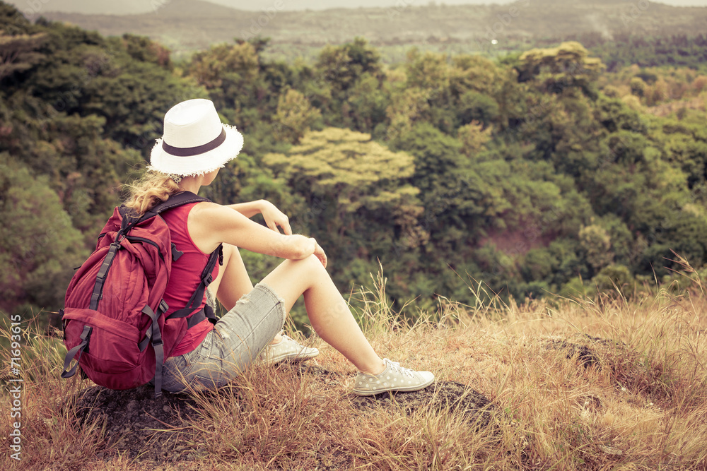 tourist with backpack relaxing on rock and enjoying admiring the