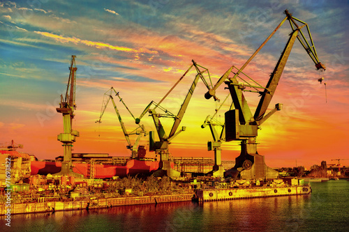 Big industrial cranes on a sunset sky background.