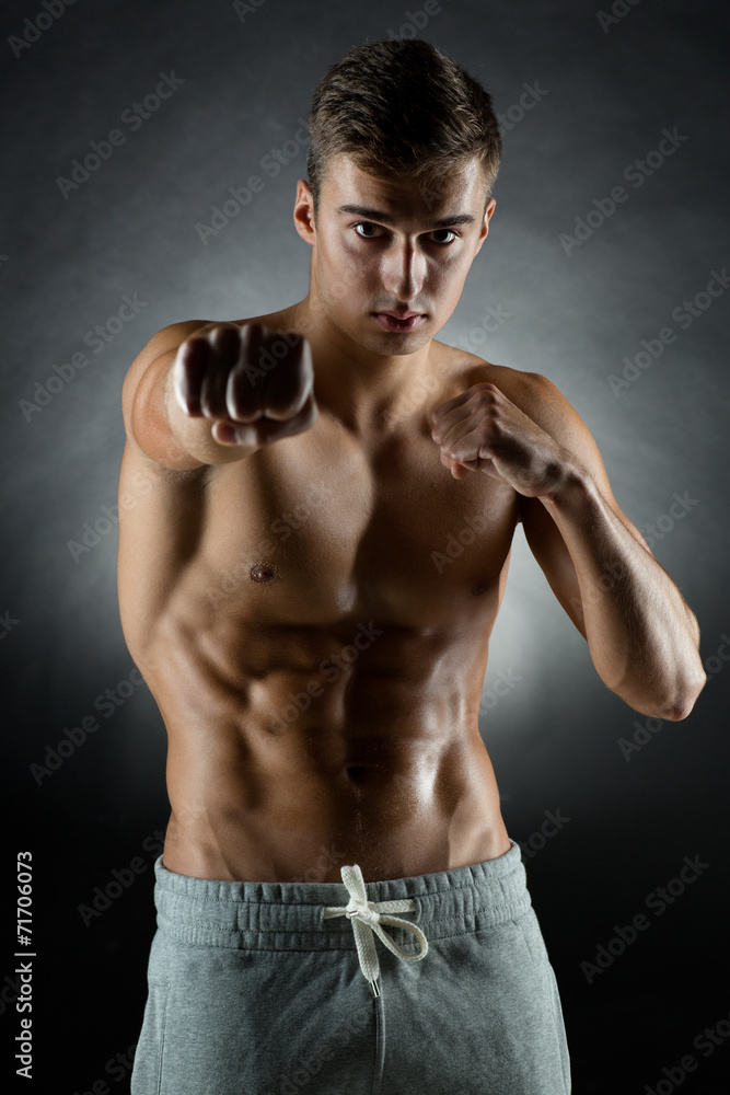 Fototapeta premium young man on fighting stand over black background