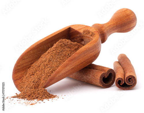 Leinwand Poster ground cinnamon spice powder in wooden spoon isolated on white b