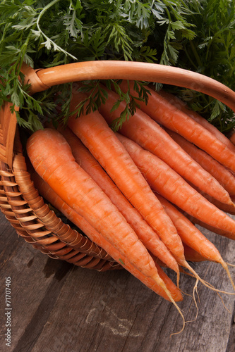 fresh carrots in wicker basket bunch on grungy wooden background