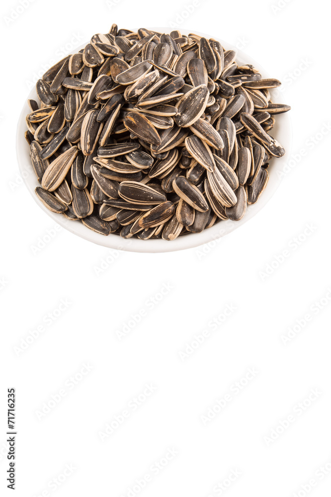 Sunflower seeds in white bowl over white background Sunflower seeds in white bowl over white background
