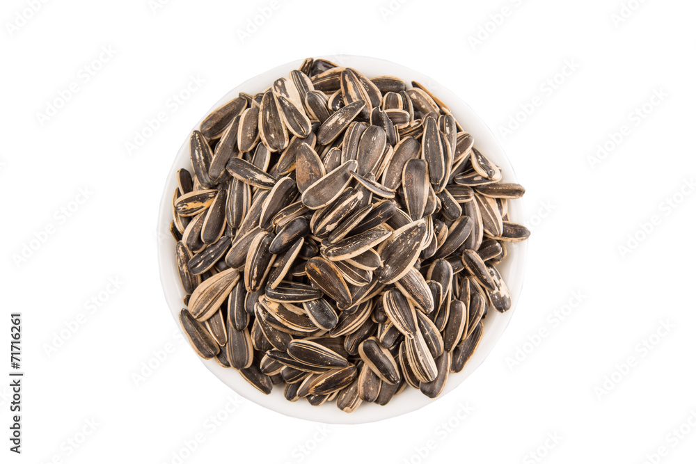 Sunflower seeds in white bowl over white background Sunflower seeds in white bowl over white background