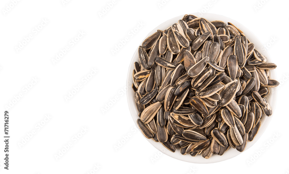 Sunflower seeds in white bowl over white background Sunflower seeds in white bowl over white background