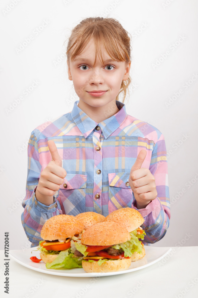 Little blond girl with big homemade hamburgers showing thumbs up