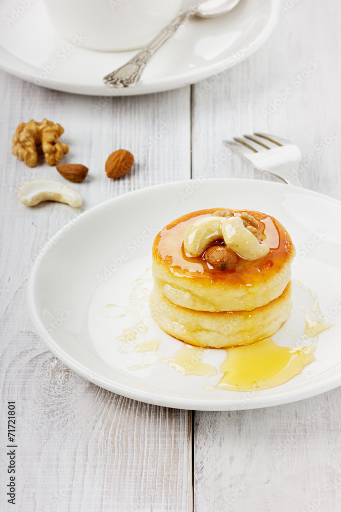 Fritters of cottage cheese with honey and nuts on a white plate