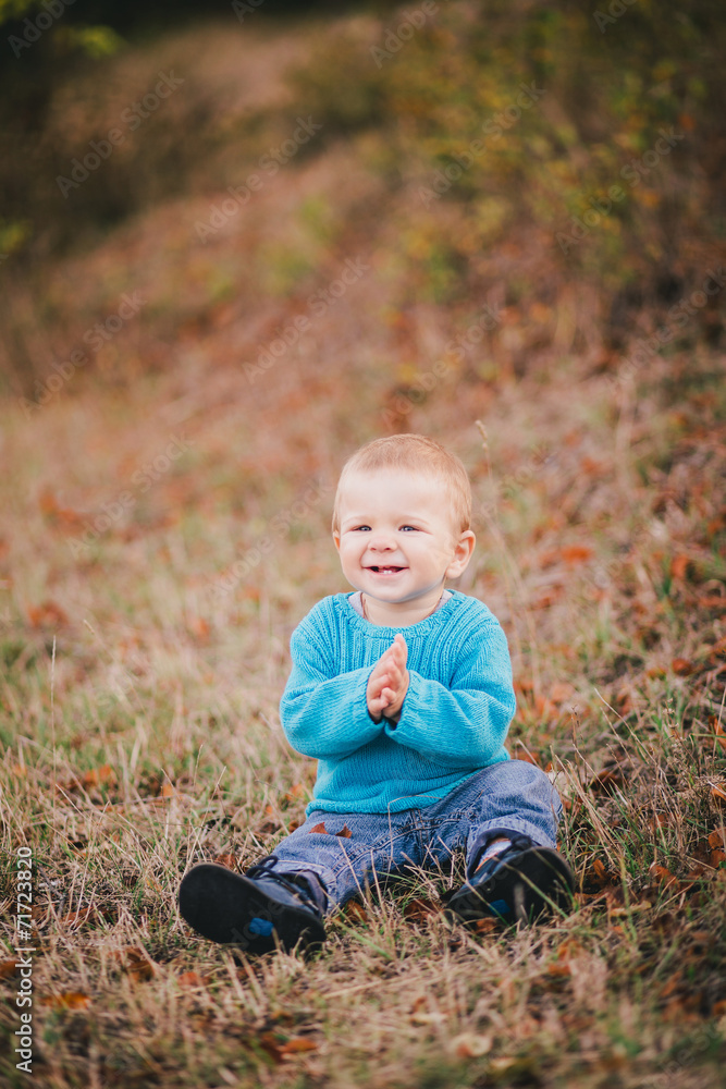 Little fashion boy in a forest wearing blue sweater and jeanse Little fashion boy in a forest wearing blue sweater and jeanse