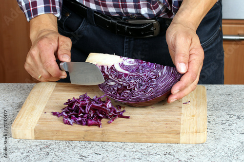 Mann bearbeitet rohen Rotkohl mit Messer, kochen