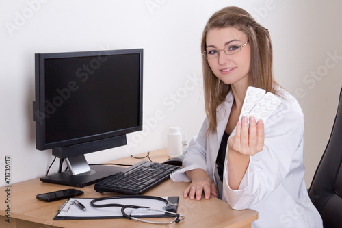 young woman doctor showing pills packages and monitor with empty