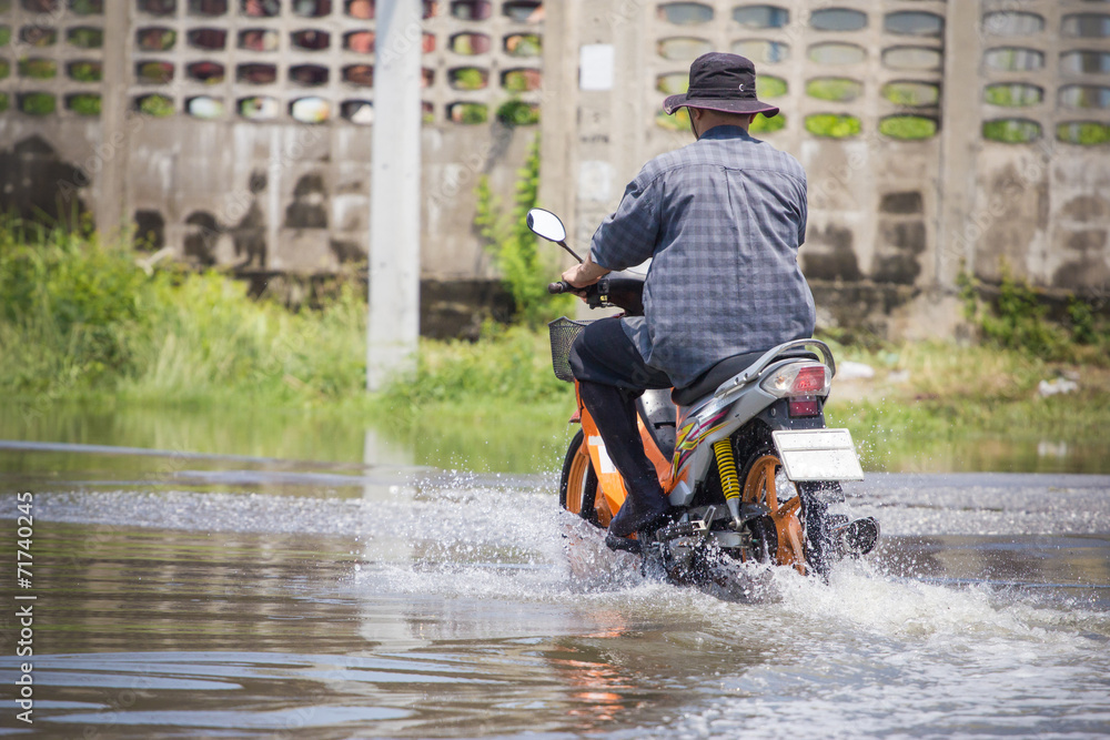 Naklejka premium Splash by a motorcycle as it goes through flood water