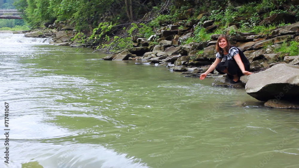 nice woman sits and plays with water on shore of mountain river nice woman sits and plays with water on shore of mountain river