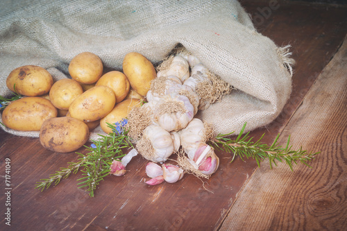 Potatoes and garlic in canvas sack on rustic wooden table