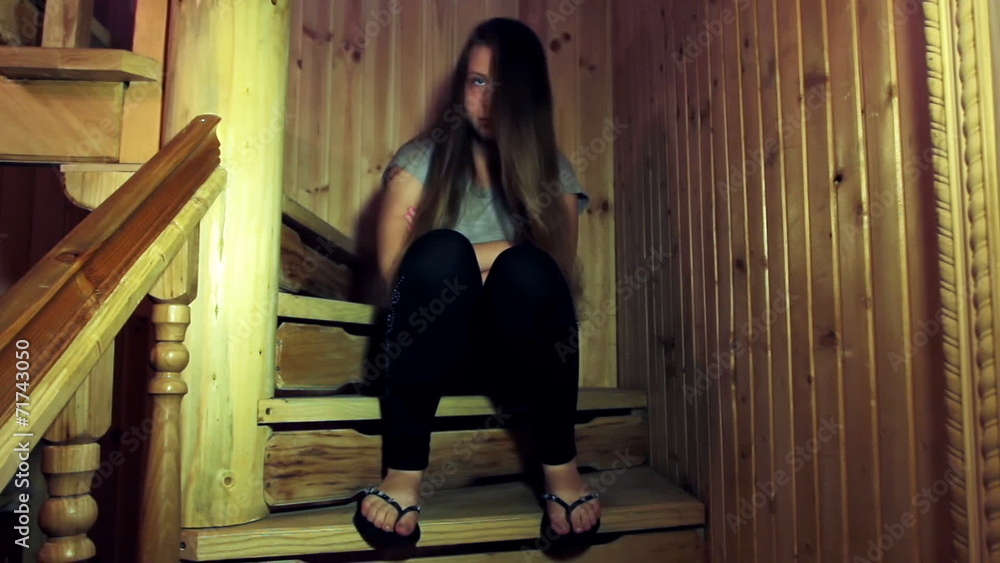 sad teen girl sits on wooden stairs in home sad teen girl sits on wooden stairs in home