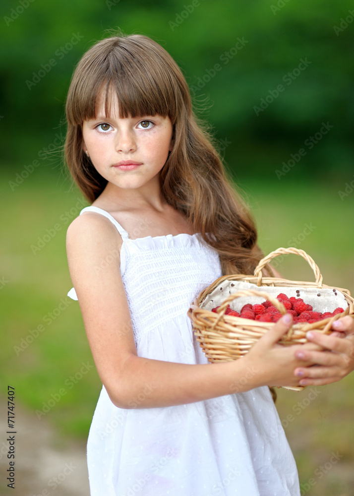 portrait of a beautiful little girl with raspberries
