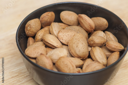Almonds on a black bowl on wooden background