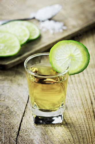 Tequila shot with lime and salt on rustic wooden background