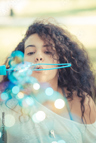 young beautiful moroccan curly woman blowing bubbles