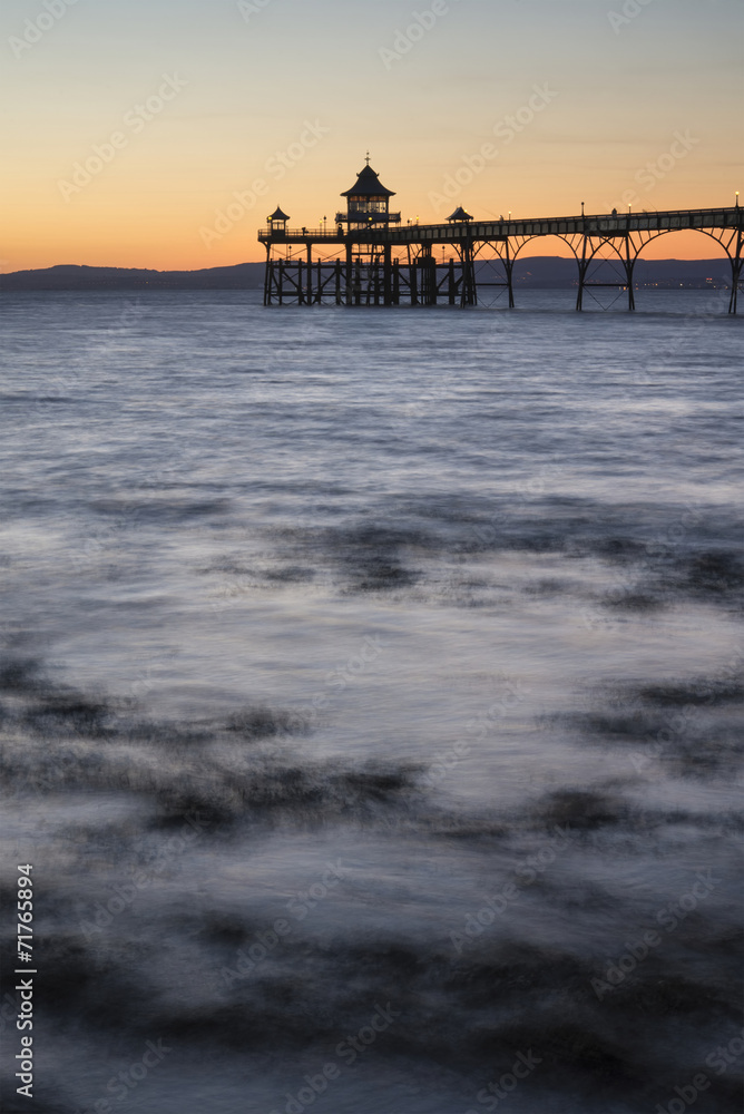 Long exposure landscape image of pier at sunset in Summer