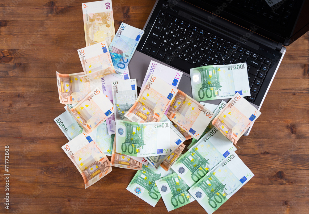 Pile of euro money with Laptop on the table Stock Photo | Adobe Stock