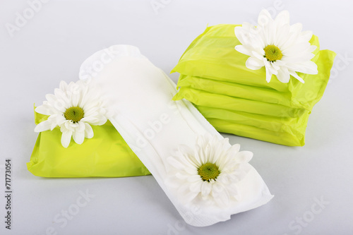 Fototapeta Naklejka Na Ścianę i Meble -  Sanitary pads and white flowers on light background