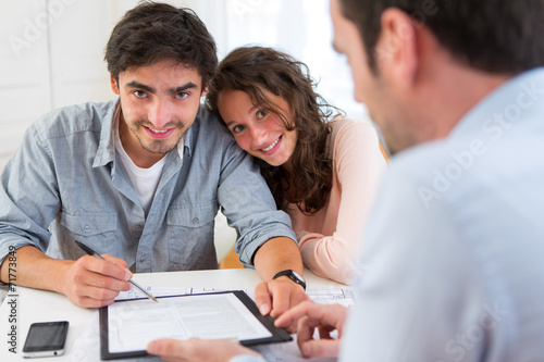 Young attractive couple signing contract
