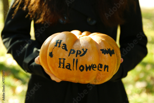 Young girl holding Halloween pumpkin, close-up, outdoors photo