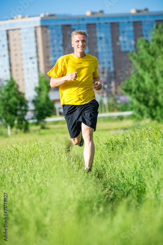 Sporty man jogging in city street park. Outdoor fitness. © mr.markin