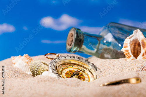 Sea Hedgehog shells and compass on sand and blue sky
